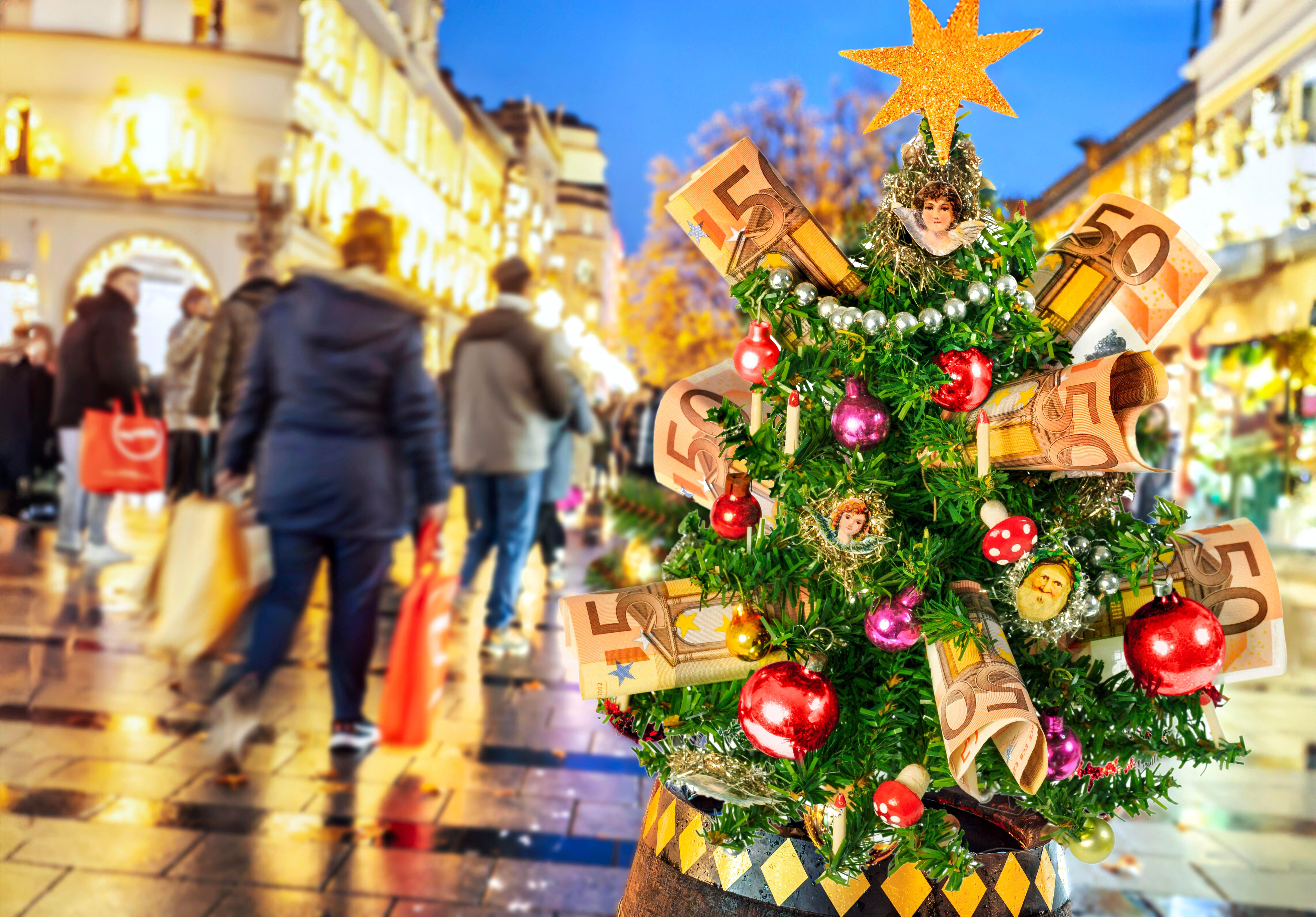 Mit Geldscheinen dekorierter Christbaum, Passanten in einer Fußgängerzone