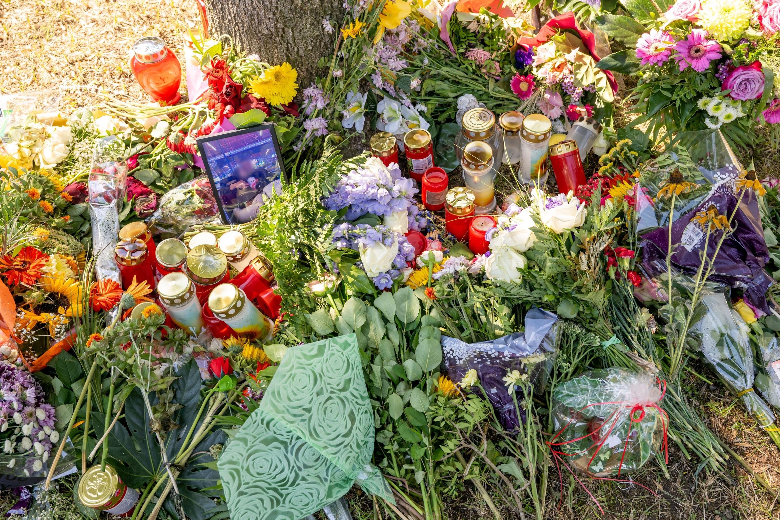 Blumen, Kerzen und ein Bild der Ermordeten liegen an einem Baum, in dessen Nähe am 17. August 2022 eine weibliche Leiche in einem Auto entdeckt wurde. 