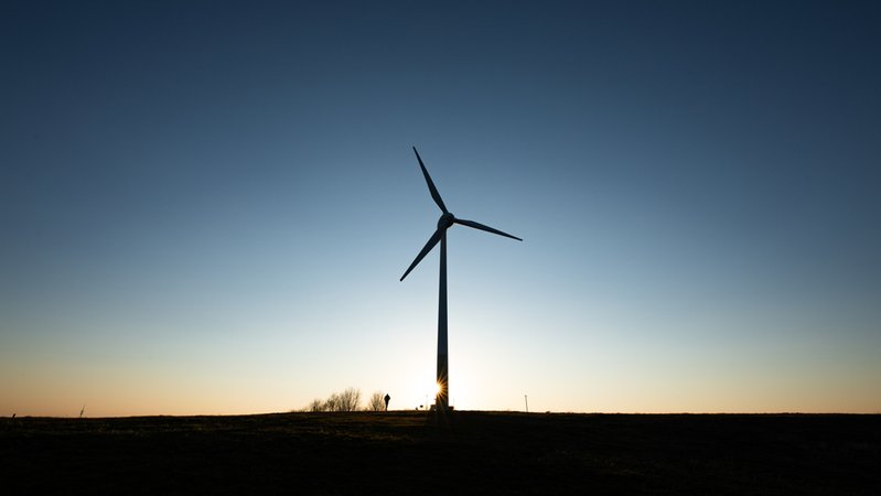Die Silhouette einer Windkraftanlage bei Sonnenuntergang.