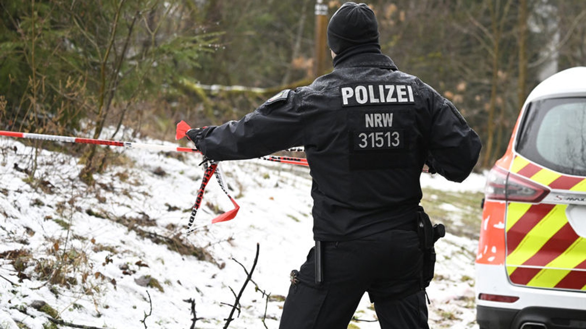 12.03.2023, Nordrhein-Westfalen, Freudenberg: Ein Polizist sperrt die Umgebung nahe des Fundorts einer Leiche weiträumig ab. Die seit Samstagabend vermisste Zwölfjährige aus dem südwestfälischen Freudenberg ist tot. Bei dem am Sonntagmittag gefundenen weiblichen Leichnam handele es sich um das gesuchte Mädchen, teilte die Polizei Koblenz am Abend mit. Foto: Roberto Pfeil/dpa +++ dpa-Bildfunk +++