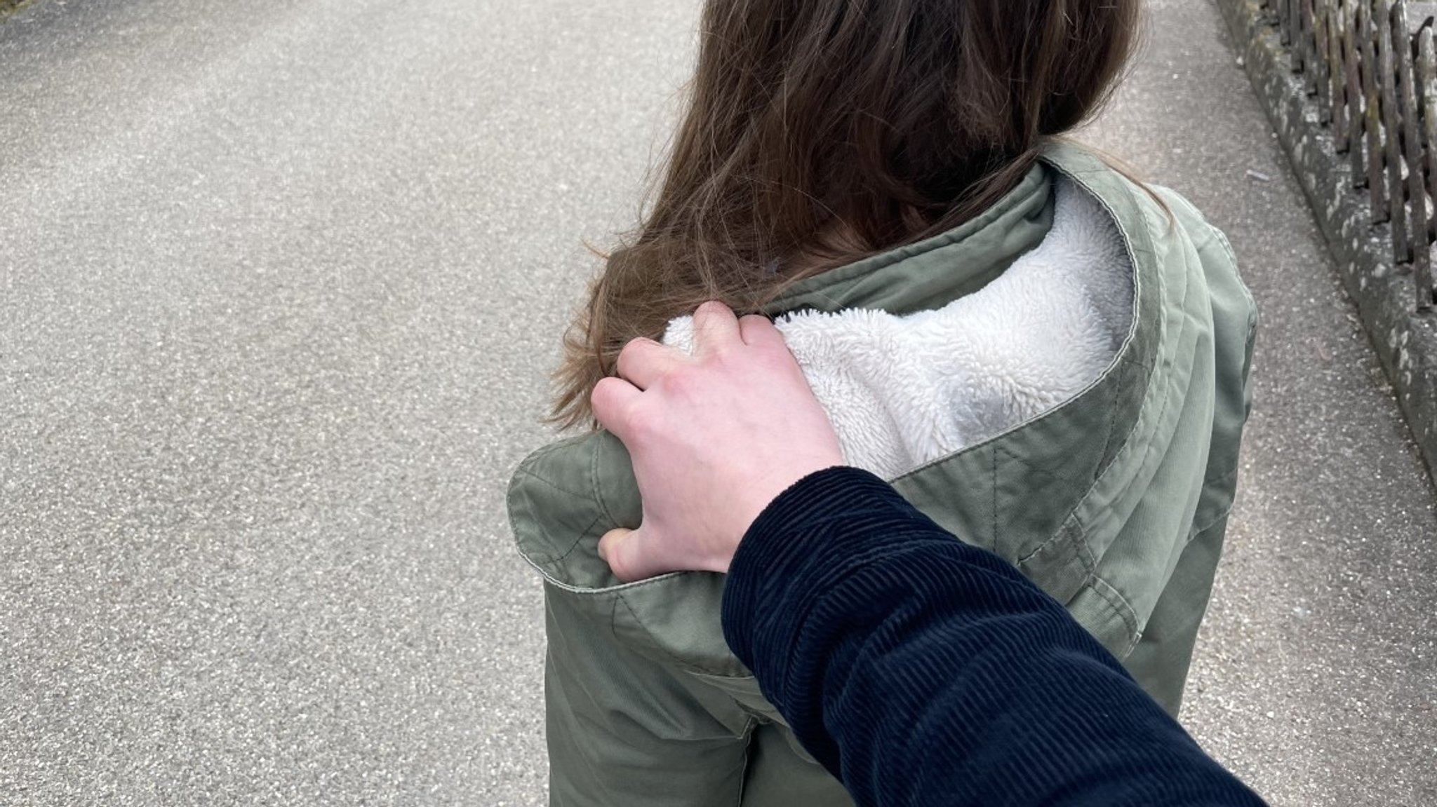 Ein Mann greift einer jungen Frau von hinten an die Schulter (Symbolbild).