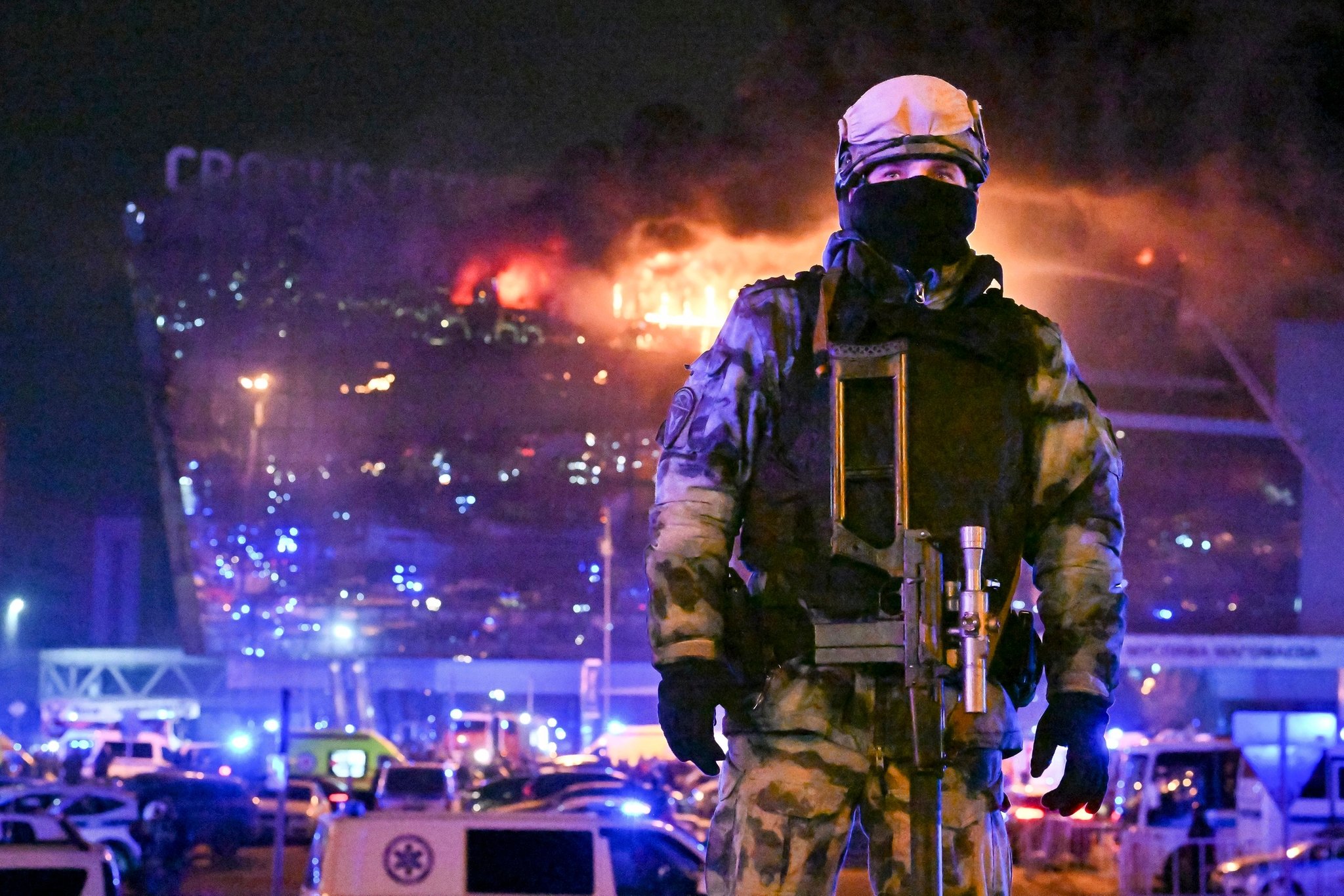 dpatopbilder - 22.03.2024, Russland, Moskau: Ein Soldat der russischen Nationalgarde (Rosgwardija) sichert ein Gebiet, während über Crocus City Hall am westlichen Rand Moskaus ein gewaltiger Brand zu sehen ist. Nach dem Angriff auf eine Veranstaltungshalle in der Region Moskau hat der russische Inlandsgeheimdienst FSB laut Agentur Interfax Tote und Verletzte bestätigt. Konkrete Zahlen zu dem mutmaßlichen Terroranschlag wurden am Freitagabend zunächst nicht genannt. Nach Behördenangaben wurden nach Schüssen und einem Brand weitere Explosionen gemeldet. Foto: Dmitry Serebryakov/AP +++ dpa-Bildfunk +++