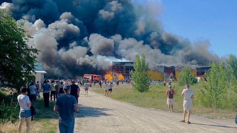 Archivbild vom 27.6.22: Nach dem Einschlag einer russischen Rakete in einem belebten Einkaufszentrum in Krementschuk, Ukraine, sehen Menschen Rauchschwaden. 