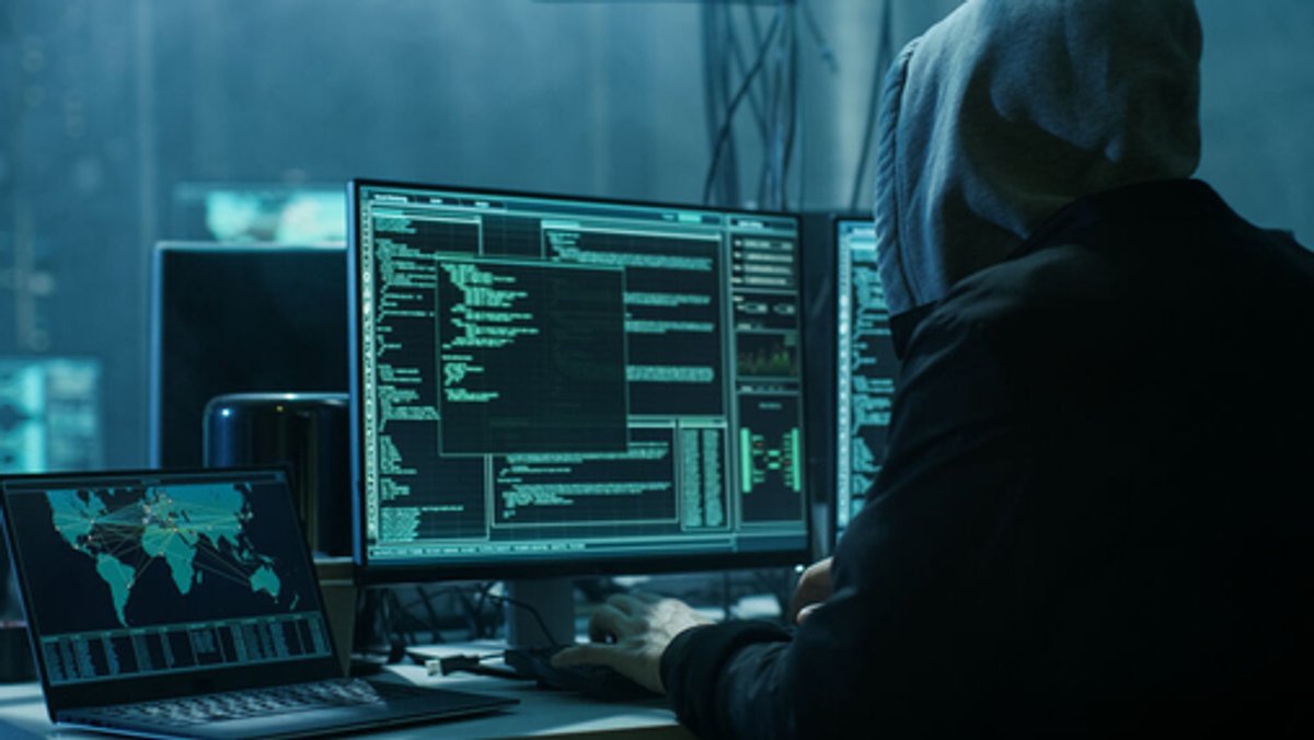 Ein Mann sitzt mit Kapuze vor einem PC und hackt. Bei einem großen Cyberangriff sind Daten von Krankenhäusern und sozialen Einrichtungen in ganz Schwaben gestohlen worden. (Symbolbild)