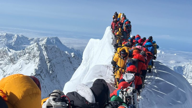 Bergsteiger in Daunenanzügen und mit Sauerstoffmasken warten am Gipfelgrat des Mount Everest. | Bild: dpa/picture alliance Bergsteiger in Daunenanzügen und mit Sauerstoffmasken warten am Gipfelgrat des Mount Everest.