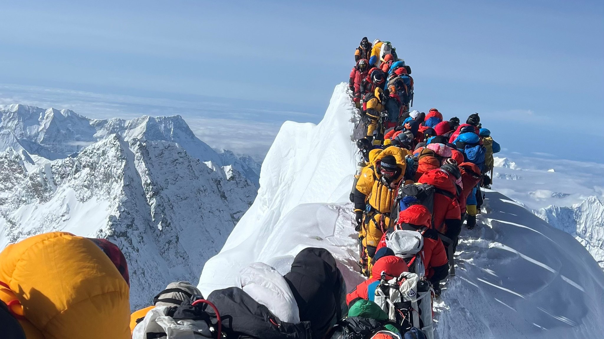 Bergsteiger in Daunenanzügen und mit Sauerstoffmasken warten am Gipfelgrat des Mount Everest.