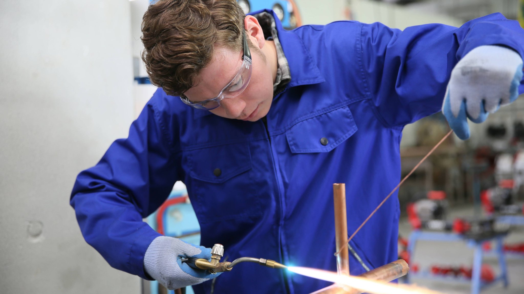 Auszubildender in der Sanitär-Berufsausbildung arbeitet an Kupfer.