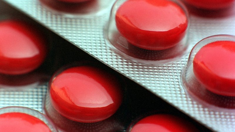 Mit roter Glasur überzogene Tabletten in ihrer Verpackung aus Plastik und Alu-Folie