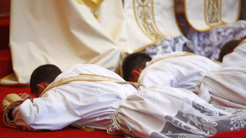 Junge Männer liegen während der Zeremonie zur Priesterweihe am Boden. 
