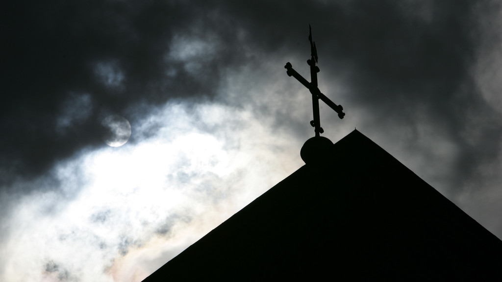 Symbolbild: Kirchenkreuz und dunkle Wolken