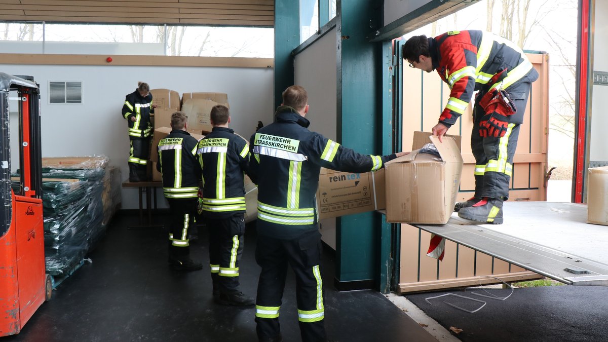 Helfer der Feuerwehr laden Hilfsgüter aus, mit der die Niederbayernhalle in Ruhstorf an der Rott für Flüchtlinge vorbereitet wird