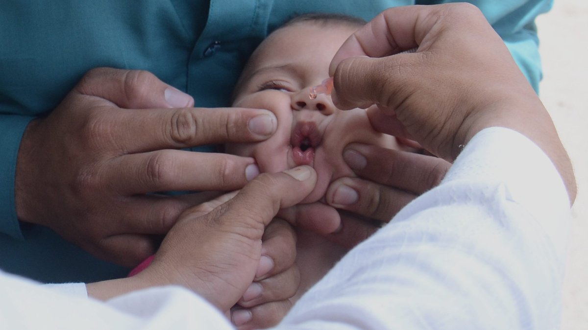 Ein Baby bekommt eine Schluckimpfung gegen Polio, also Kinderlähmung