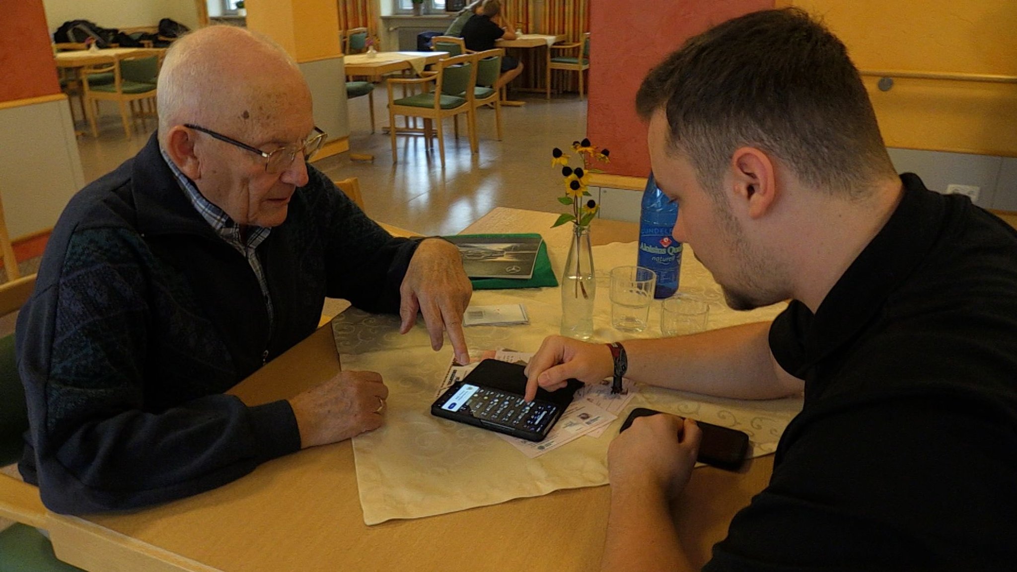 Maxim (rechts) hilft Karl Lechner mit seinem Smartphone. 