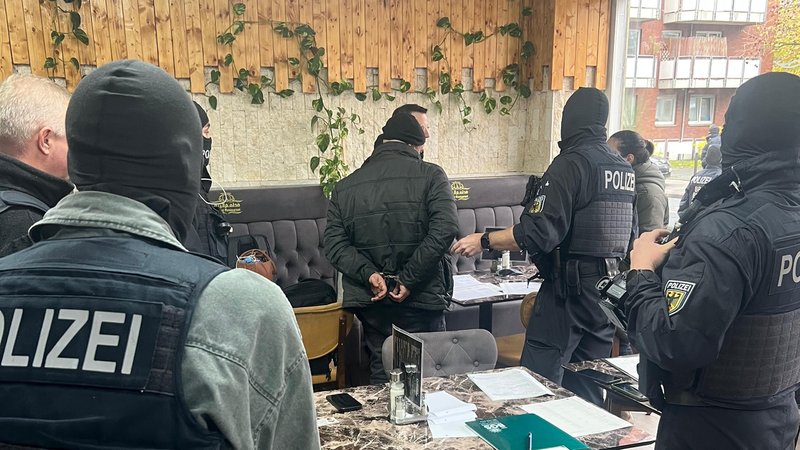 Vermummte Polizisten nehmen in einem Café mutmaßliche Mitglieder einer Schleuserbande fest. | Bild: Bundespolizei Vermummte Polizisten nehmen in einem Café mutmaßliche Mitglieder einer Schleuserbande fest.