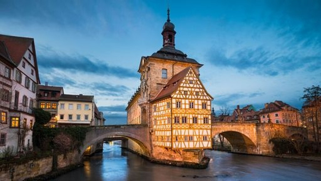 Das Alte Rathaus von Bamberg, ein Fachwerkbau auf einer Brücke, in der Dämmerung.
