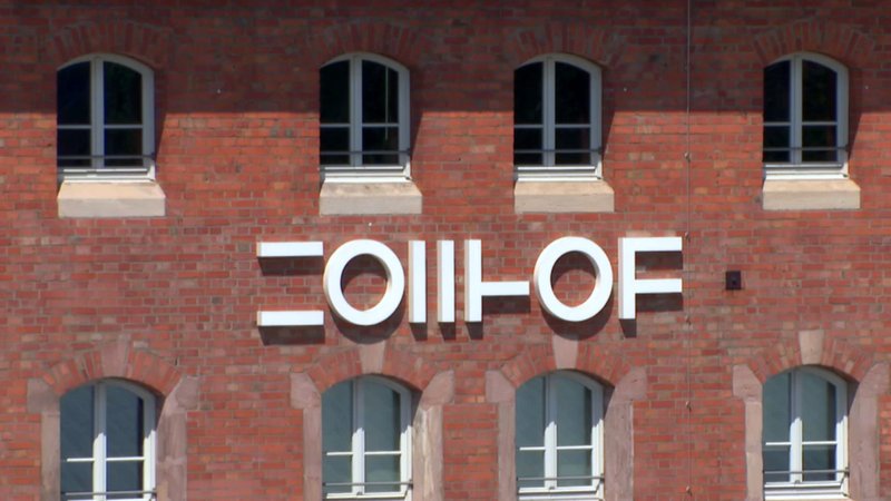 Auf einer Backstein-Fassade steht in modernen Lettern der Schriftzug: Zollhof. | Bild: BR Auf einer Backstein-Fassade steht in modernen Lettern der Schriftzug: Zollhof.