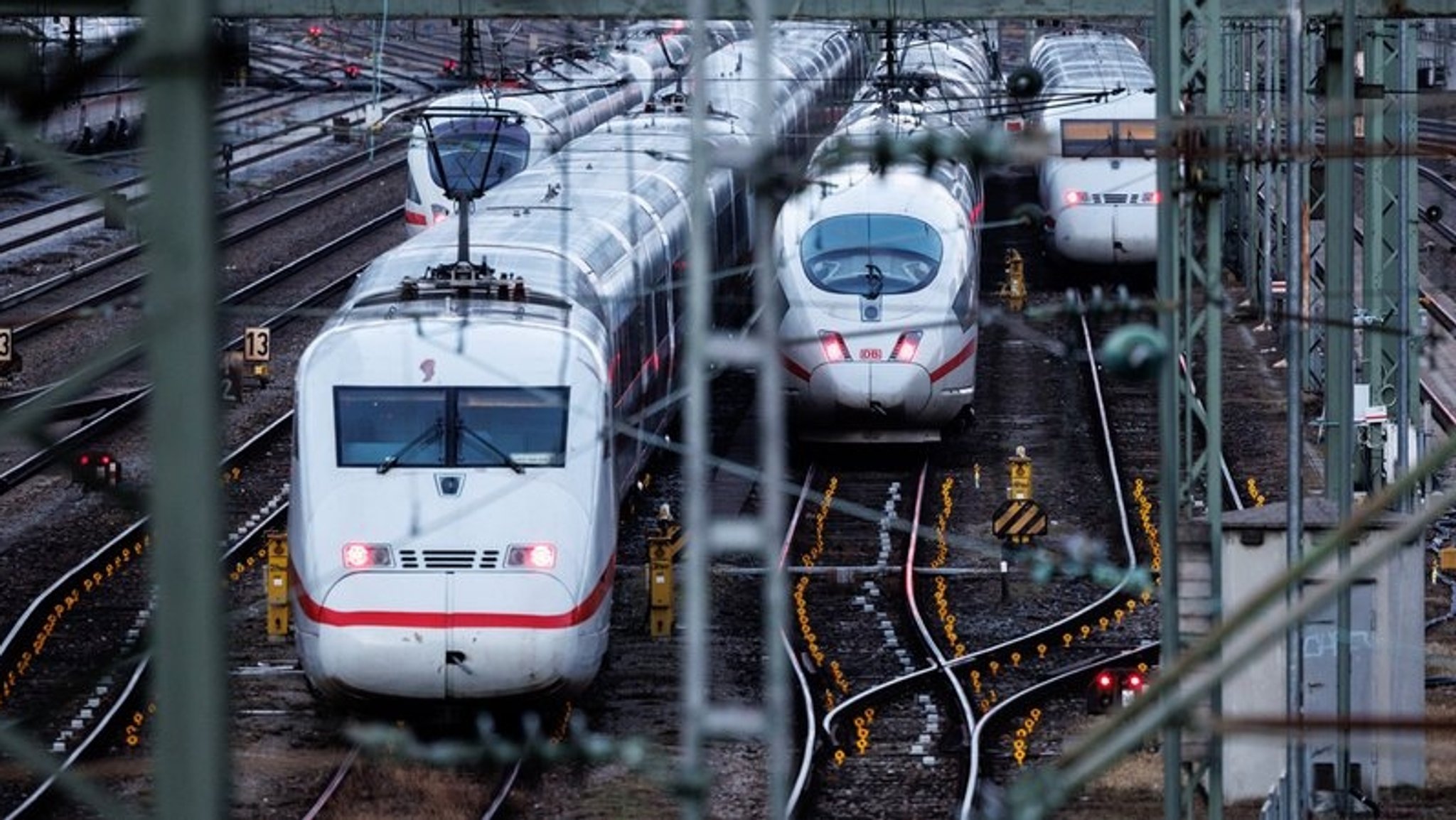 In einem Bahnhof stehen mehrere Züge des Typs ICE auf den Gleisen. 