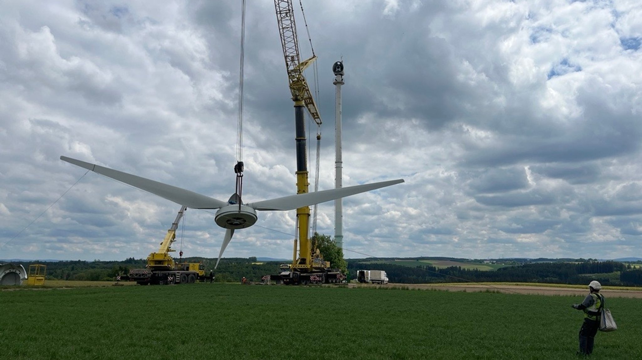 Ein Kran hebt das Rotorblatt eines Windrads in Richtung Boden. | Bild: BR/Annerose Zuber Ein Kran hebt das Rotorblatt eines Windrads in Richtung Boden.