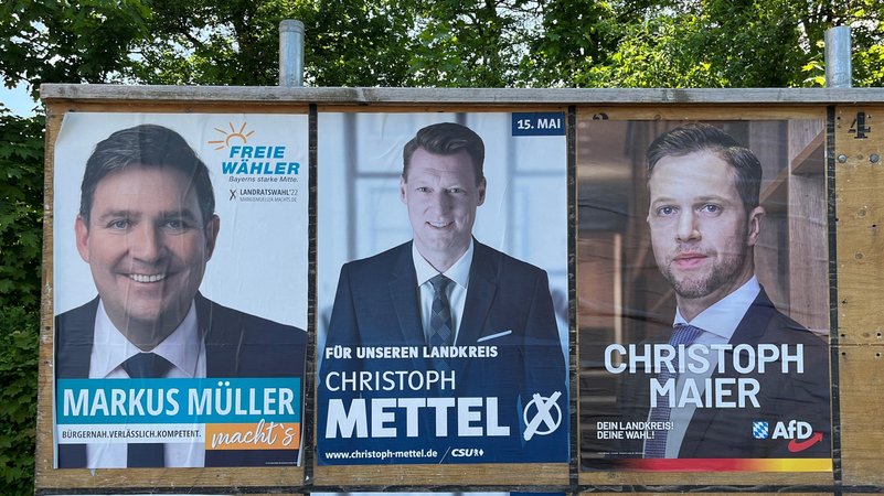 Plakatwand mit den drei Kandidaten für die Landratswahl. 