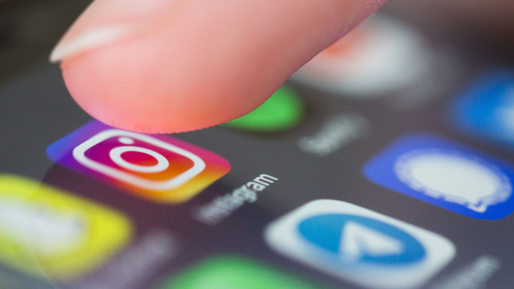 Ein Finger tippt am Handy auf die App Instagram