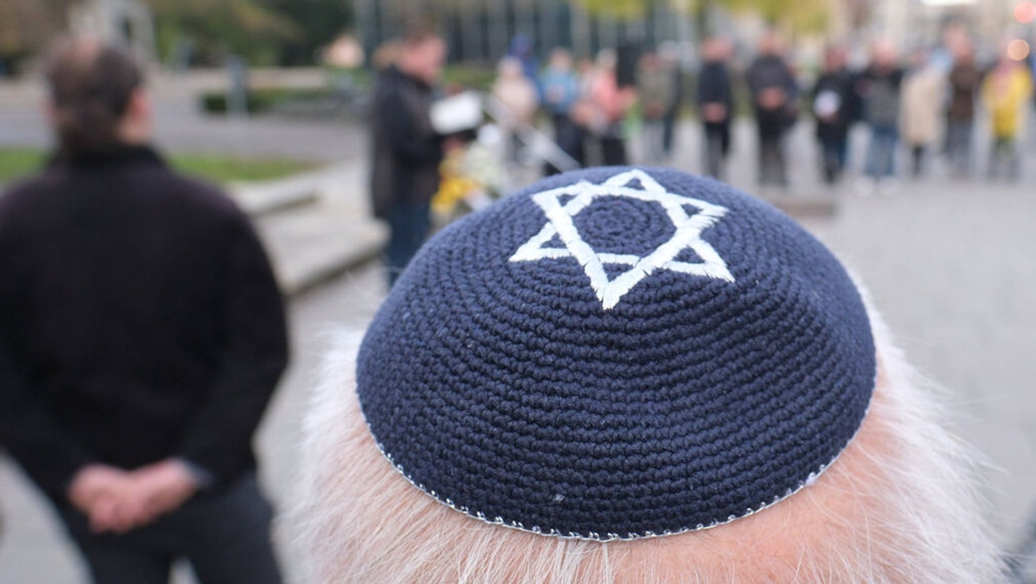 Ein Teilnehmer einer Gedenkveranstaltung trägt eine Kippa mit einem Davidstern.