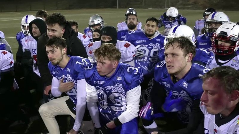 Footballspieler in blau-weißen Trikots auf dem Footballfeld. | Bild: BR Footballspieler in blau-weißen Trikots auf dem Footballfeld.