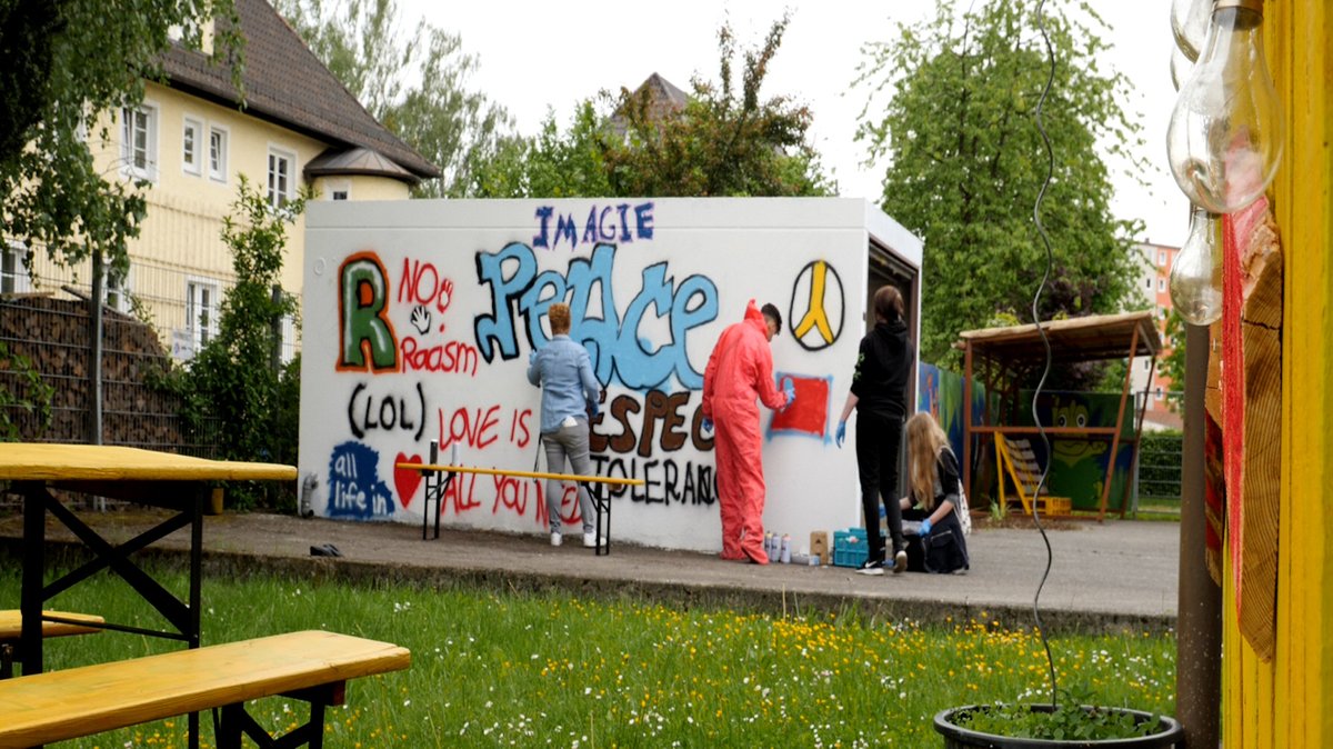 Jugendliche besprühen eine Garagenwand am Jugendzentrum Mühldorf mit Graffitis.