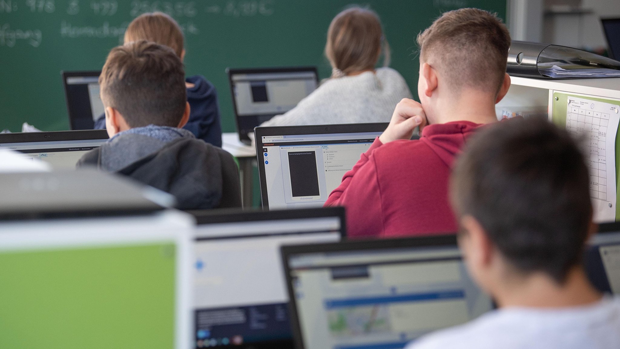 Schüler in einem Klassenzimmer arbeiten an Laptops.