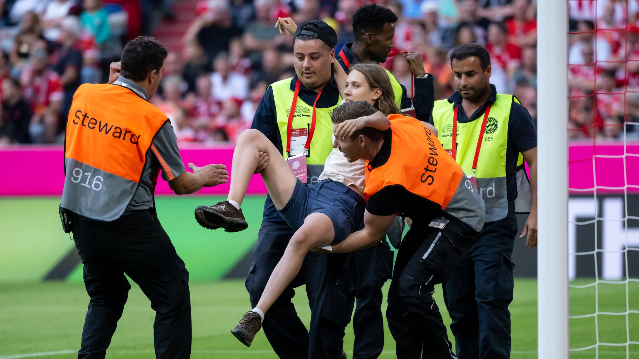 Klimaaktivisten der "Letzten Generation" werden während des Spiels am 27.08.2022 von Ordnern vom Platz getragen. Sie waren zu den beiden Toren von Bayern-Keeper Manuel Neuer und Yann Sommer gelaufen. Es schien so, als wollten sie sich an den Torpfosten festmachen.