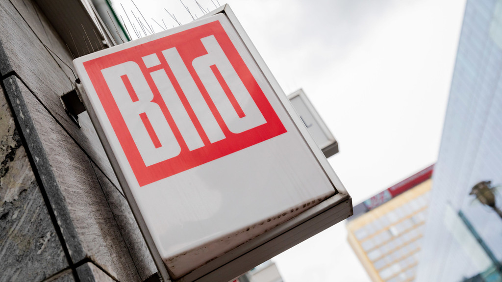 Das Logo der Boulevardzeitung "Bild" ist vor dem Axel-Springer-Hochhaus (hinten r) an einem Kiosk zu sehen.