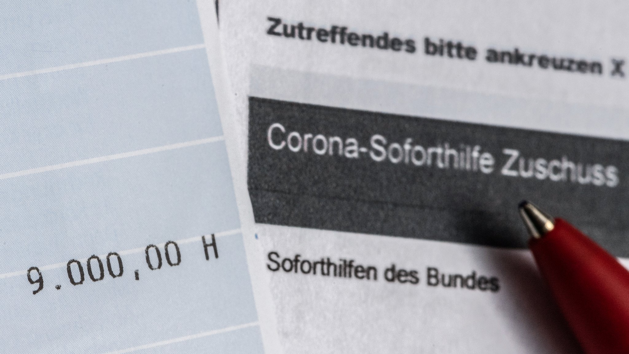 Ein Kontoauszug mit der überwiesenen Summe von 9.000 Euro Corona-Soforthilfe liegt auf einem Antrag für den Zuschuss der Sächsischen Aufbaubank.