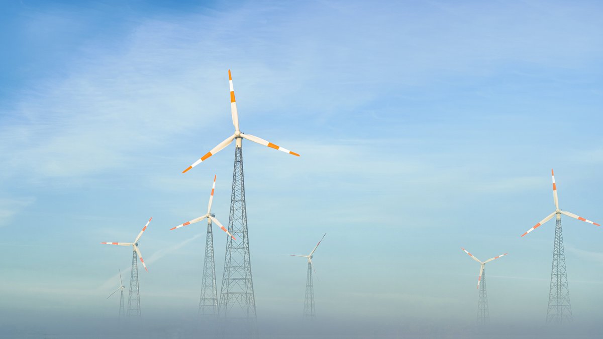 Windräder vor blauem Himmel im Nebel; Kraftwerksstrategie: Reicht der Strom bei Dunkelflauten?