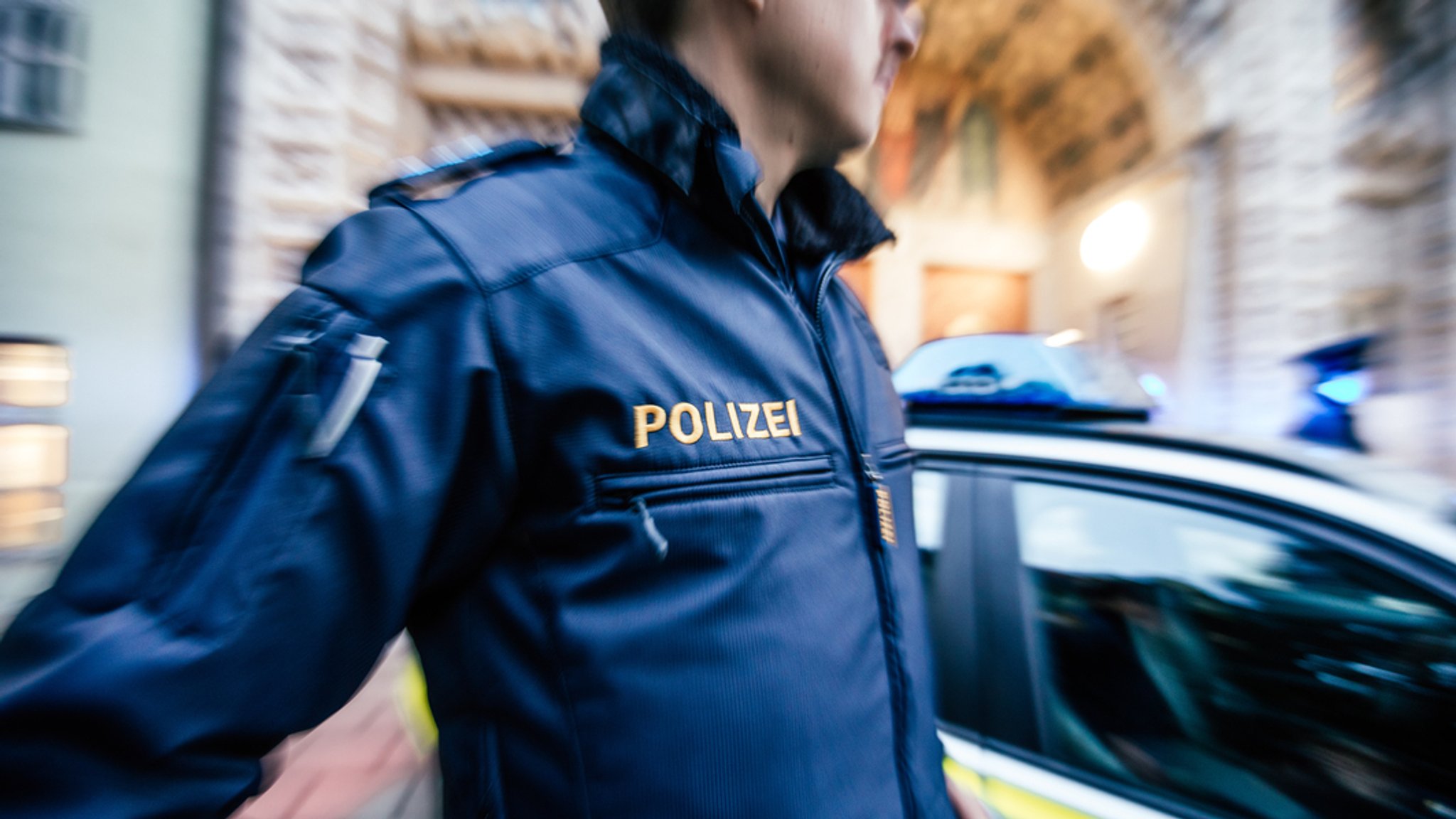 Ein Polizist steht vor einem Polizeiauto.