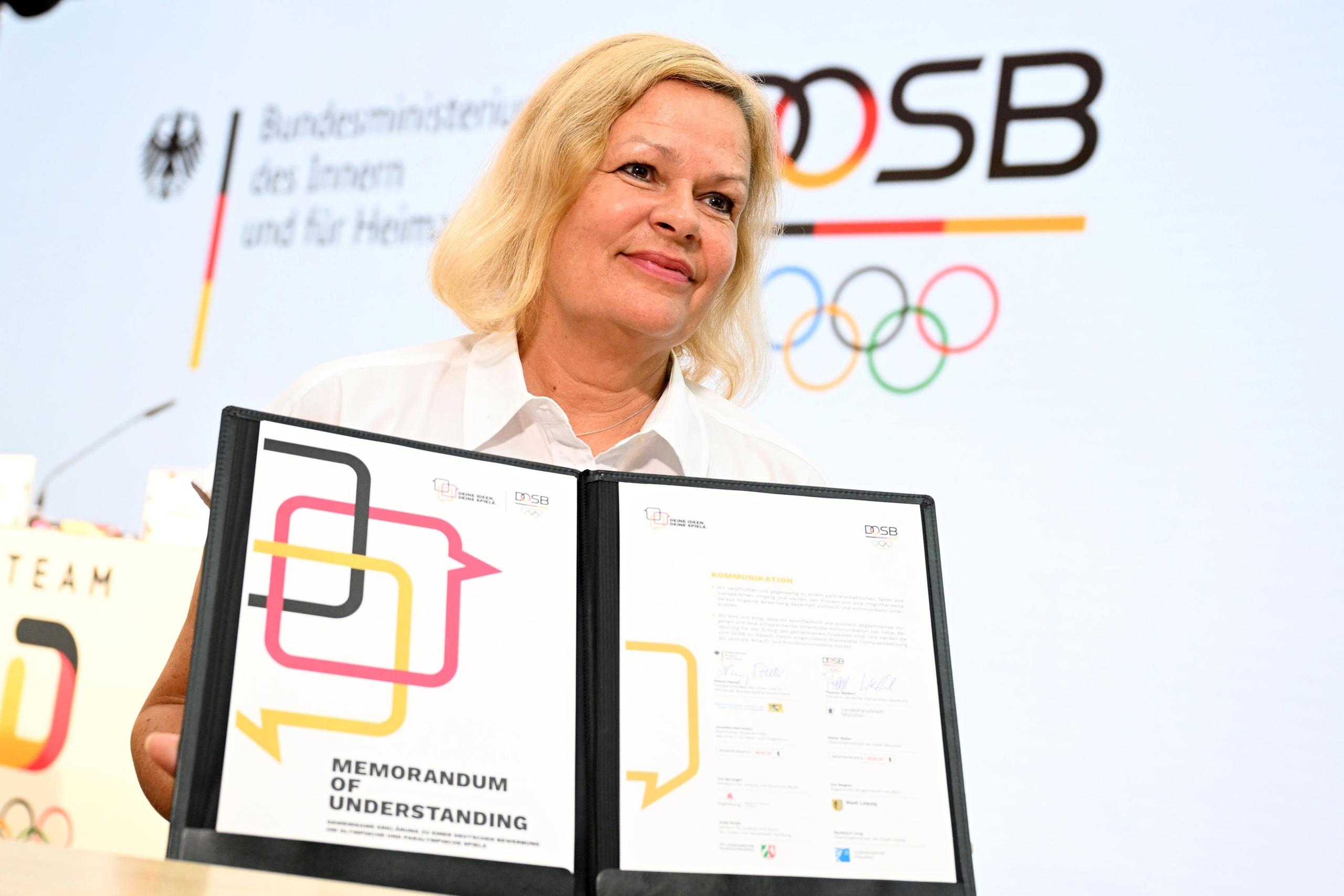 Bundesinnenministerin Nancy Faeser hält eine Grundlagenvereinbarung für einen neuerlichen Anlauf für Olympia in Deutschland in den Händen