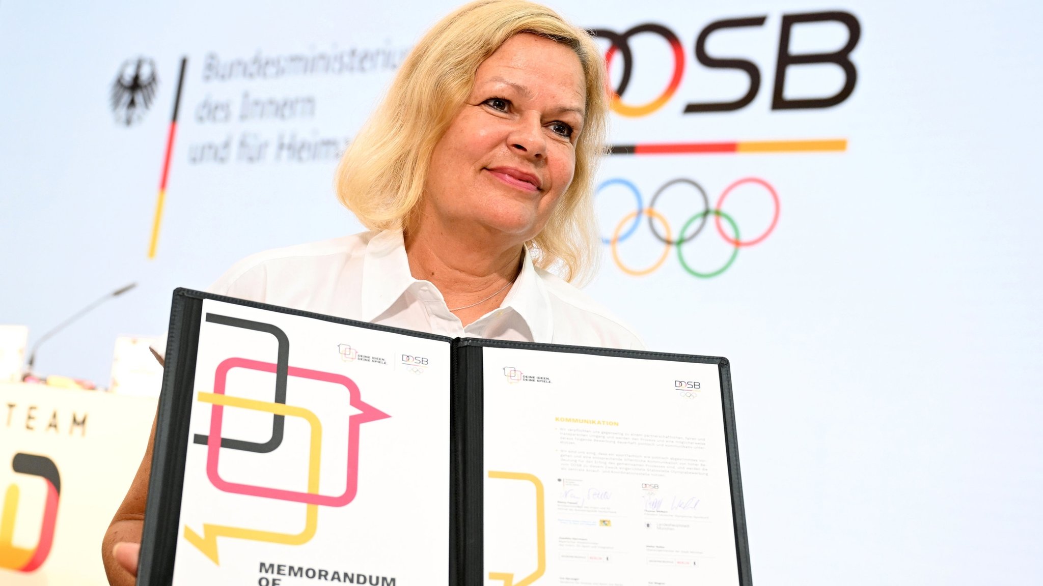 Bundesinnenministerin Nancy Faeser hält eine Grundlagenvereinbarung für einen neuerlichen Anlauf für Olympia in Deutschland in den Händen