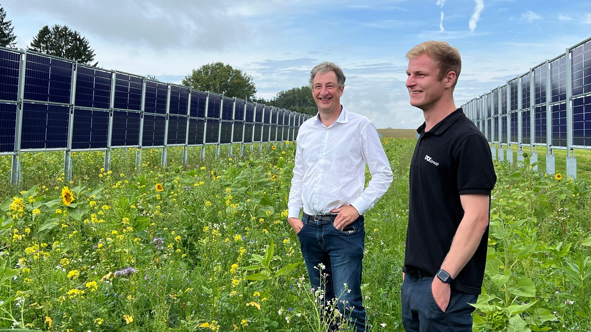 Franz Obermayer Junior und Senior stehen zwischen zwei Reihen mit vertikalen Photovoltaikmodulen.