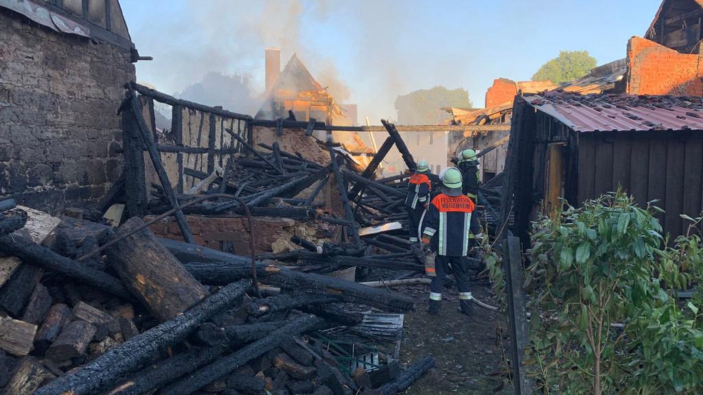 Einsatzkräfte der Feuerwehr stehen an einem abgebrannten Gebäude. | Bild: BR Einsatzkräfte der Feuerwehr stehen an einem abgebrannten Gebäude.