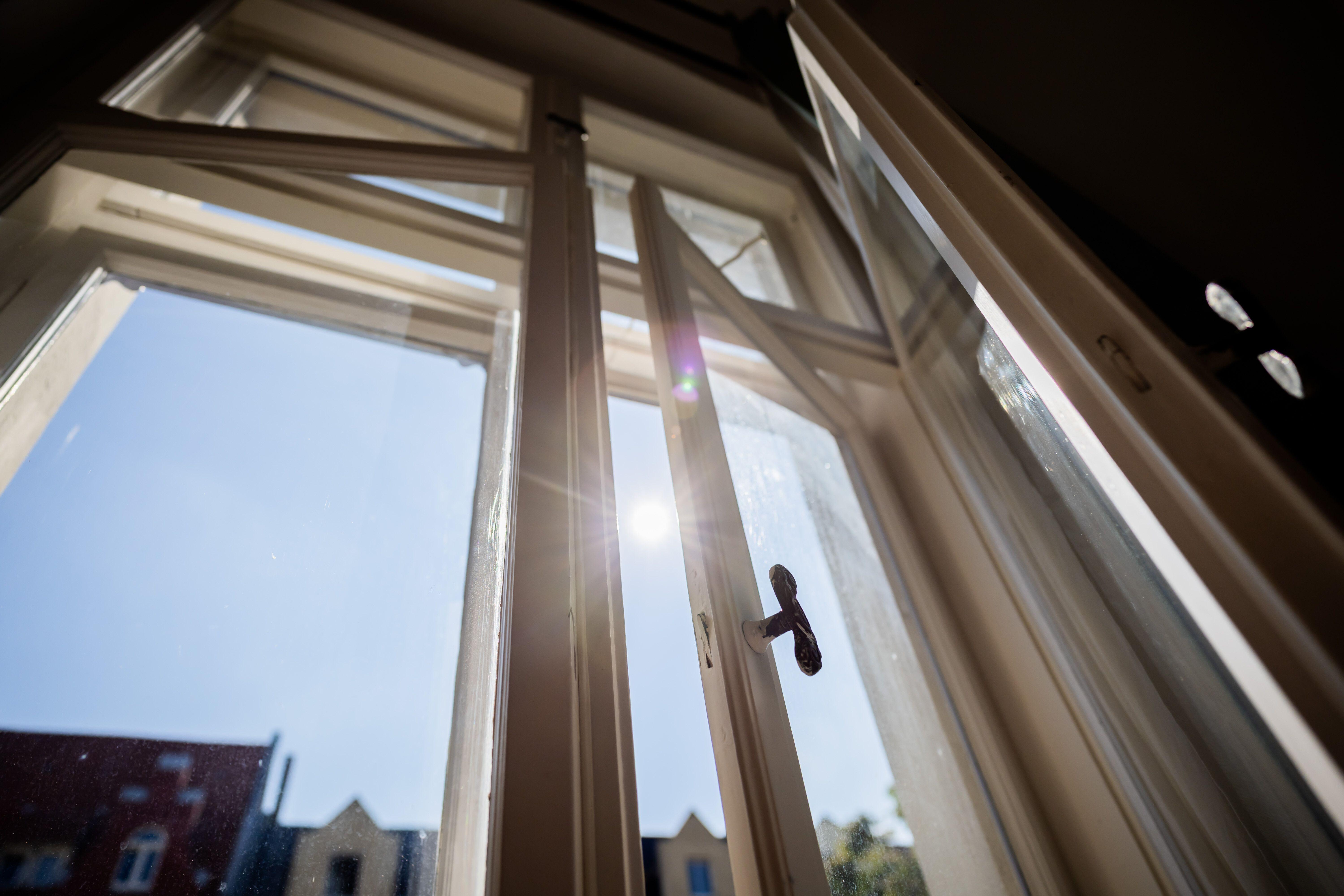 Ein geöffnetes Fenster mit gleißender Sonne am Himmel