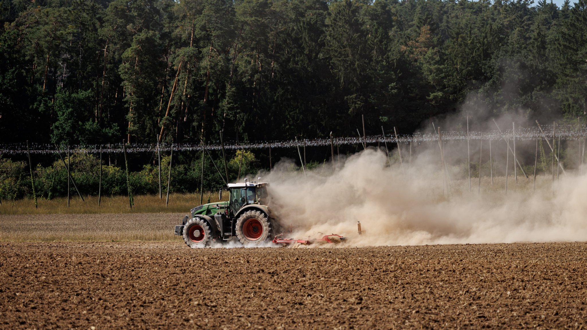 (Symbolbild) Ein Landwirt bearbeitet in Mittelfranken mit seinem Traktor ein abgeerntetes Getreidefeld und wirbelt dabei Staub vom trockenen Boden auf.
