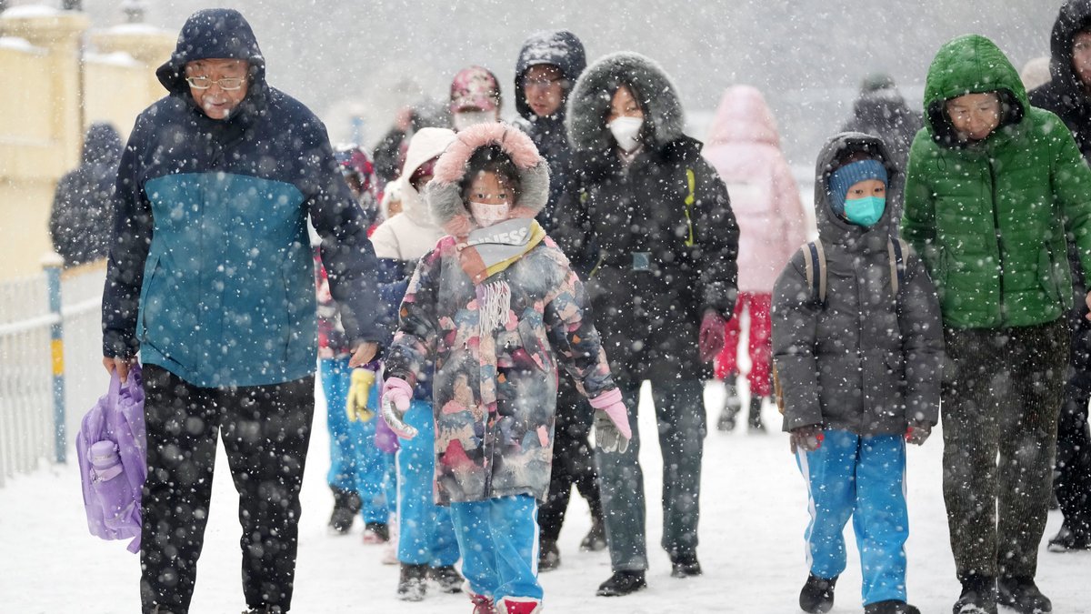 China, Harbin: Auf diesem von der Nachrichtenagentur Xinhua veröffentlichten Foto bringen Eltern in der Hauptstadt der nordostchinesischen Provinz Heilongjiang ihre Kinder bei Schneefall zur Schule