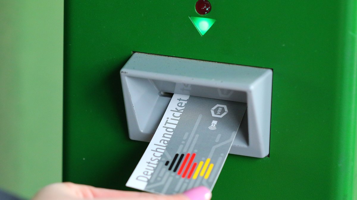 Jemand zieht ein Deutschlandticket aus einem Fahrkartenautomaten (Symbolbild)
