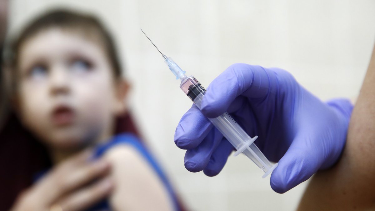 Kind guckt ängstlich auf die Impfspritze