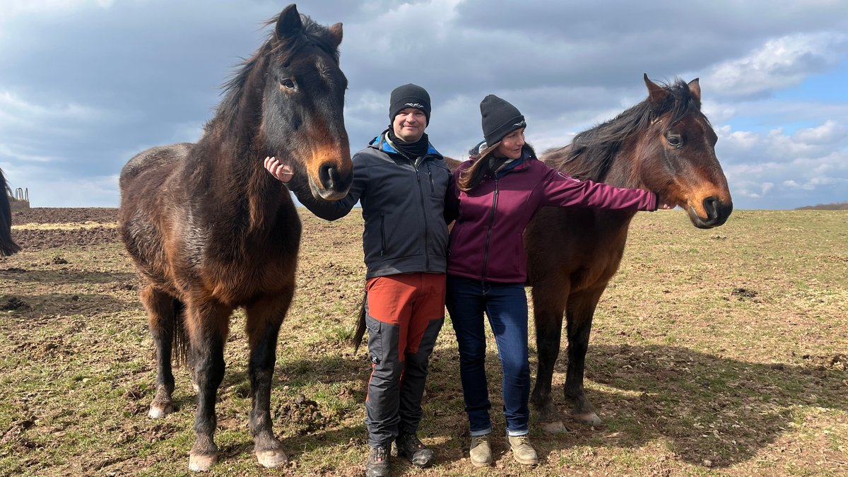 Hendrik und Charlotte Kiefner stehen zwischen zwei Pferden auf einer Weide auf dem Grieshof