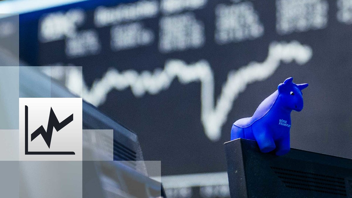 ein blauer Stier aus Gummi sitzt auf der oberen Kante eines Bildschirmes, im Hintergrund die Kurstafel der Börse.