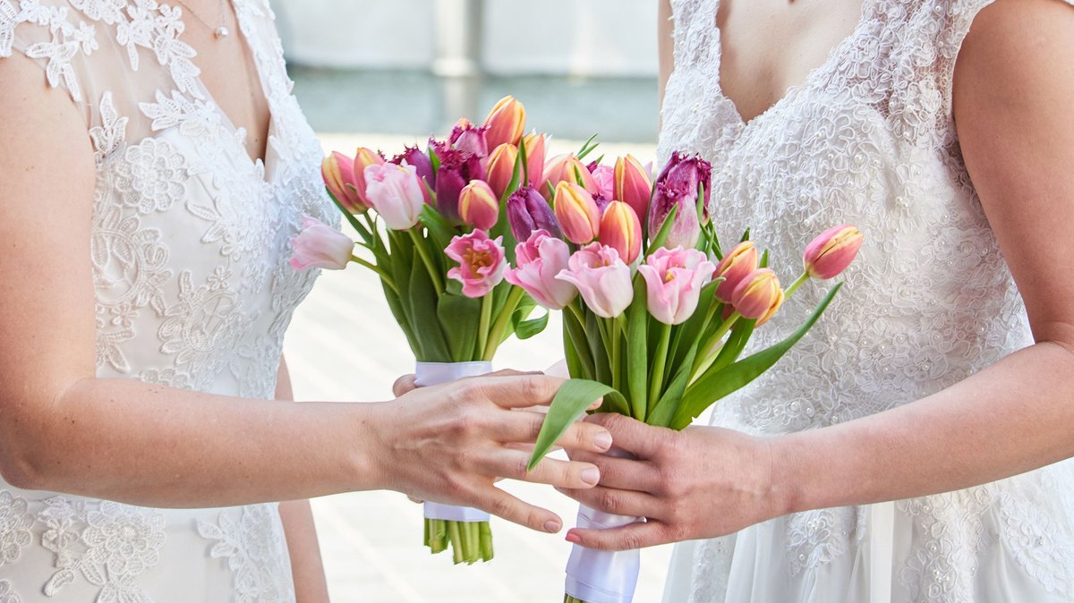 Zwei Frauen im Brautkleid mit Blumenstrauß bei ihrer Hochzeit