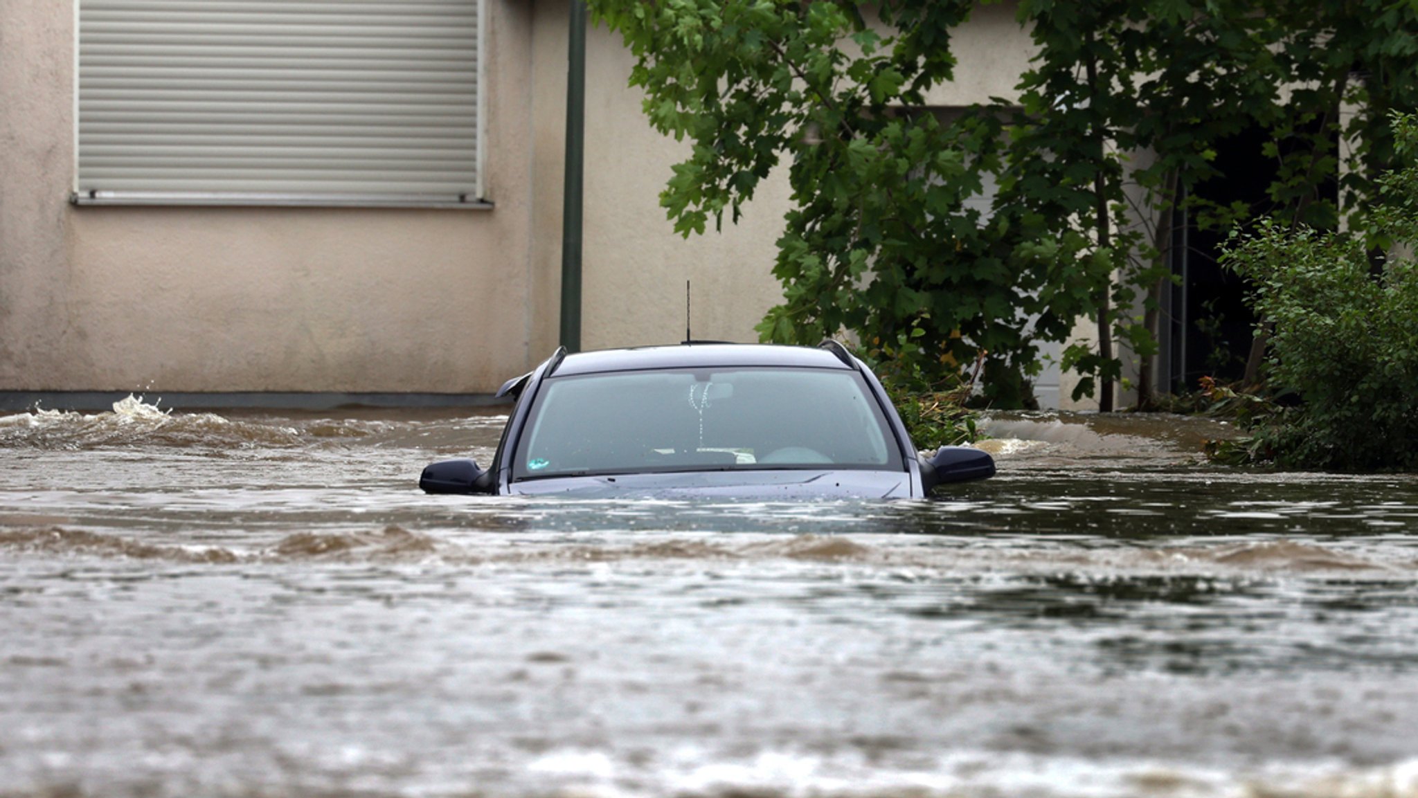 Ein Auto steht im Hochwasser der Mindel in einem Wohngebiet.