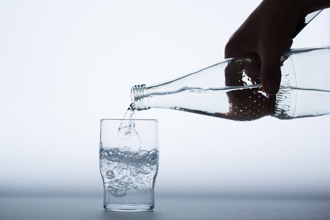 Mineralwasser wird in ein Glas eingegossen.