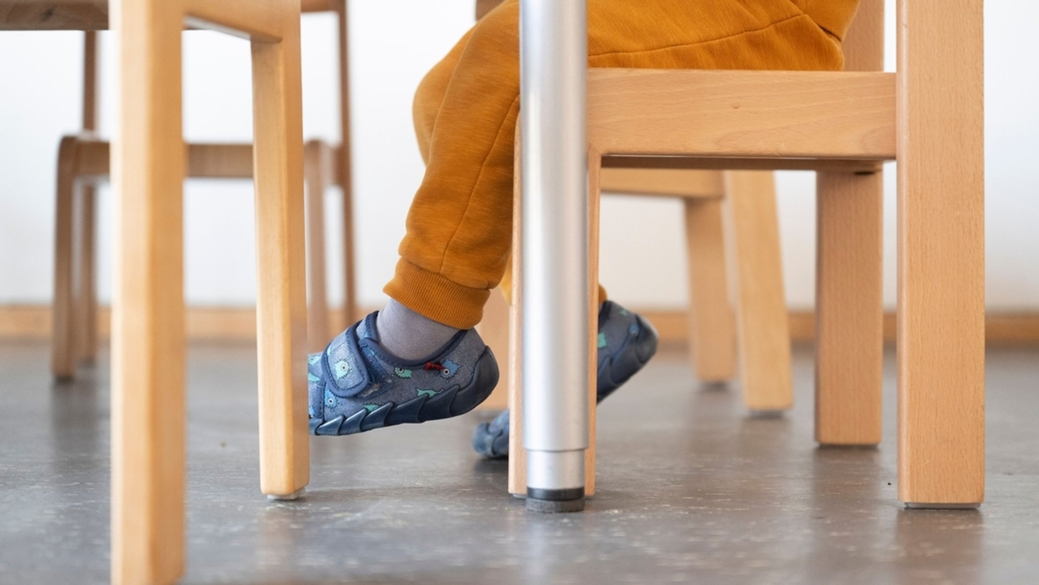 Ein Kind sitzt auf einem Stuhl und wartet in einer Tageseinrichtung für Kinder auf sein Mittagessen. 