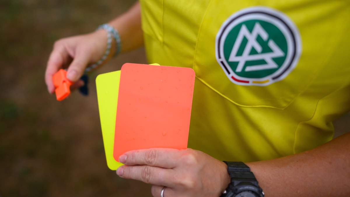 Schiedsrichterin mit roter und gelber Karte in der Hand