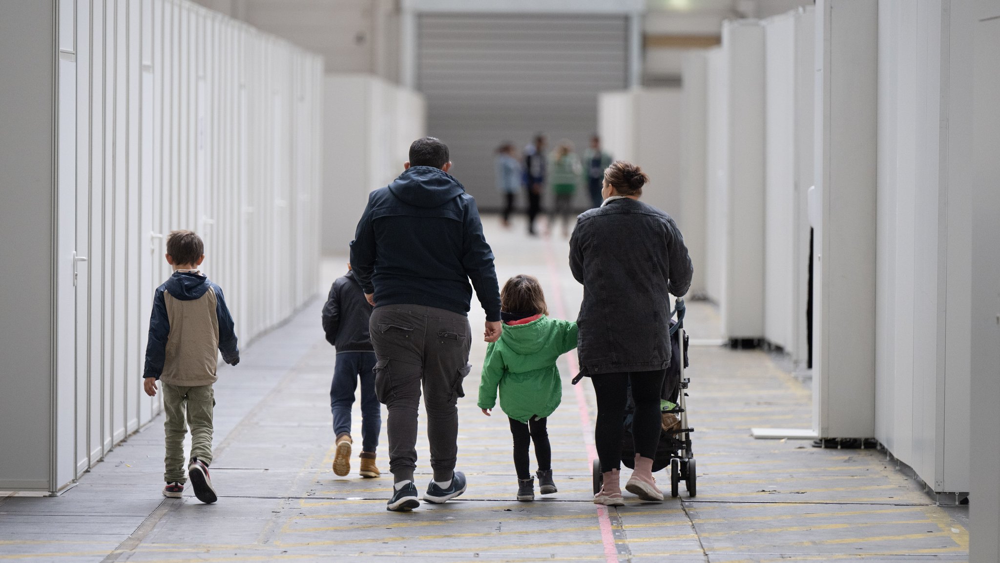 Eine Familie Geflüchteter geht durch die zu einer Massenunterkunft umfunktionierten Messehalle in Frankfurt (Archivbild)